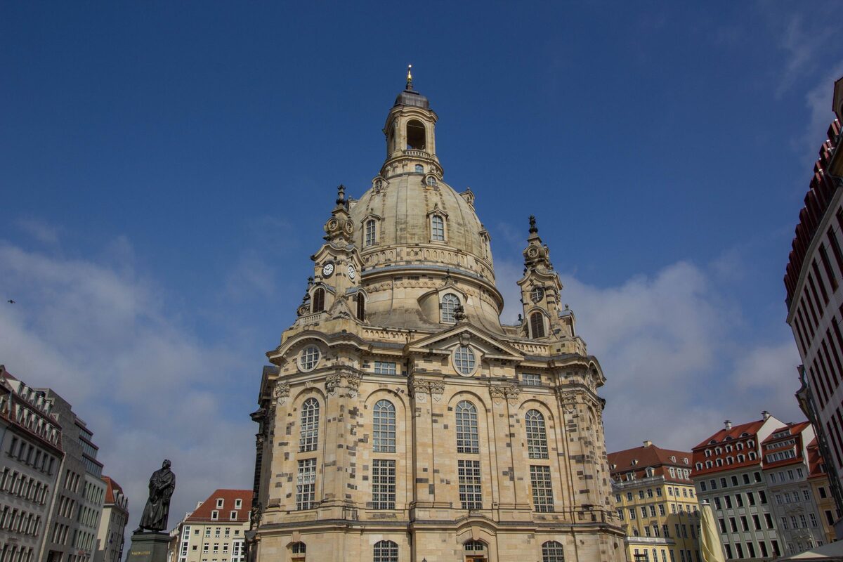 The Frauenkirche dome and its corner towers against a deep blue sky, seen from the Neumarkt