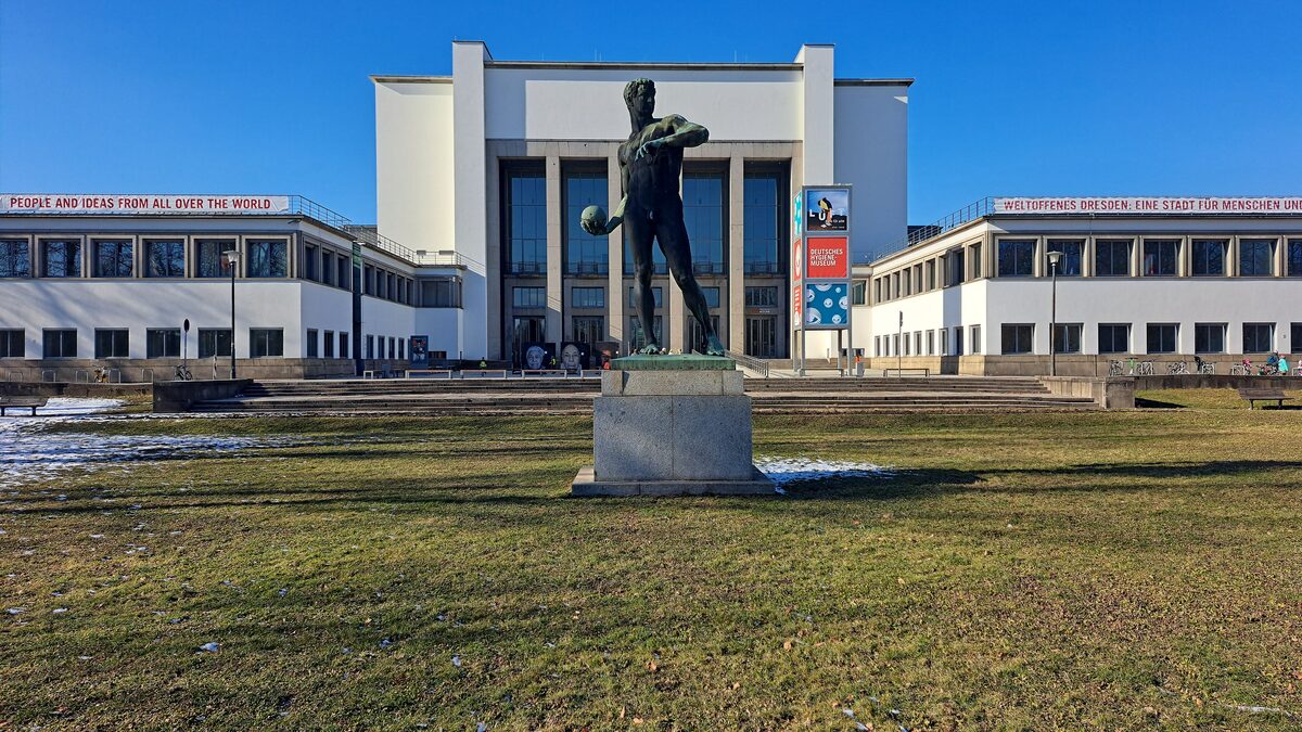 The pale 1930 facade of the Deutsches Hygiene-Museum behind a bronze statue of a ball thrower on the lawn