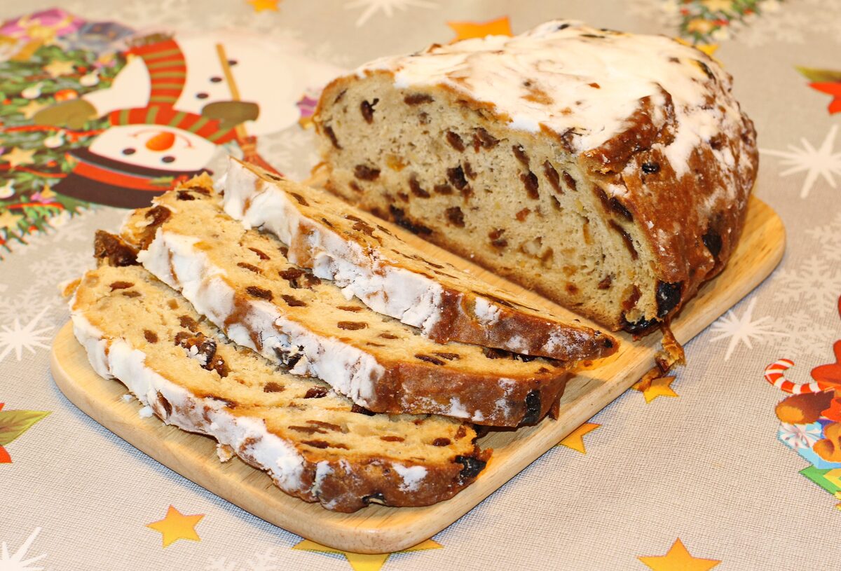 A sliced Dresdner Christstollen dusted with icing sugar on a wooden board