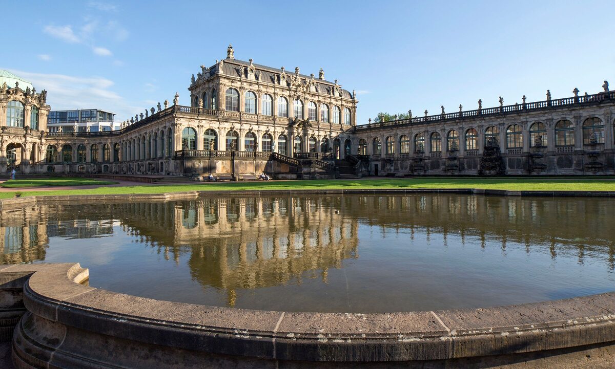 A baroque pavilion and gallery of the Zwinger reflected in the round pool in its courtyard