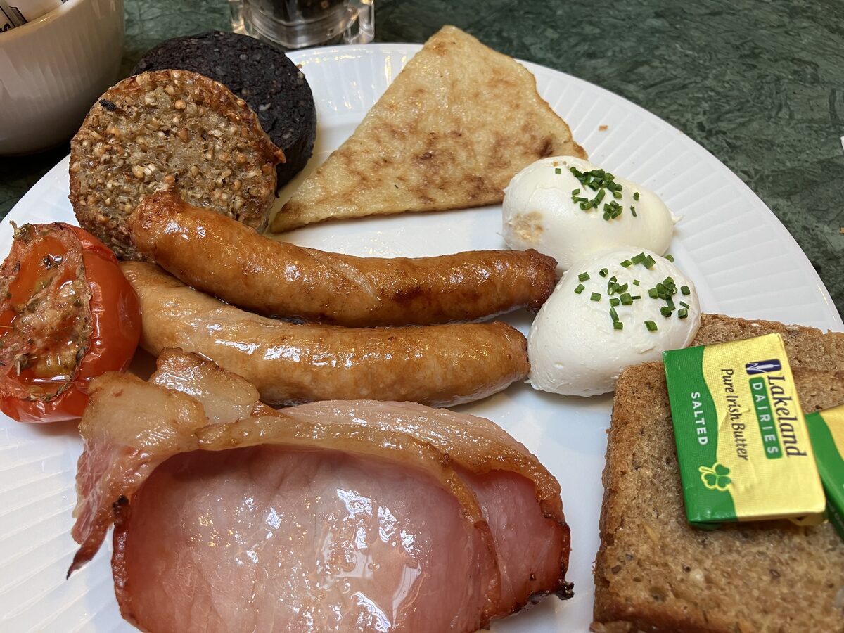 A full Irish breakfast with sausages, rashers, black and white pudding, poached eggs, grilled tomato, a triangle of boxty and brown bread with butter