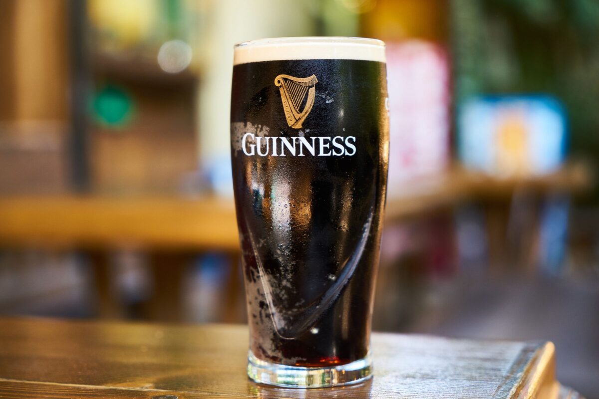 A pint of Guinness with a creamy white head on a wooden pub table