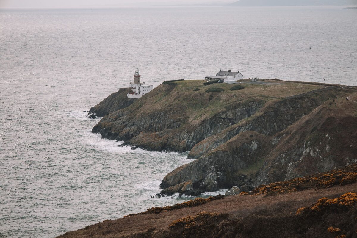 The Baily Lighthouse on a rocky headland at the tip of Howth Head, with heather in the foreground and the gray Irish Sea around it