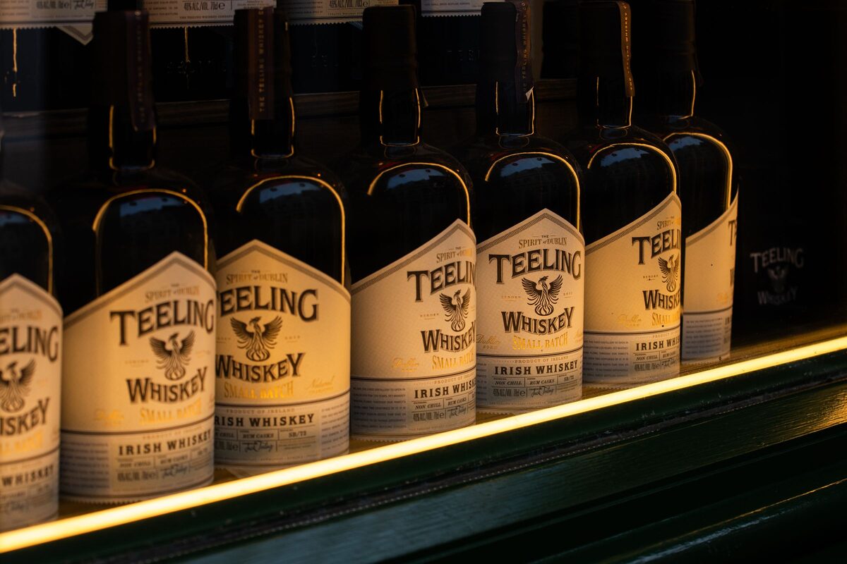 A row of Teeling Irish whiskey bottles lit from below on a dark shelf