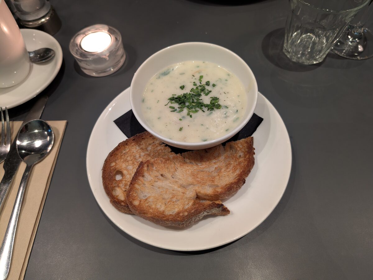 A bowl of creamy Cullen skink soup with chives, with slices of toasted bread on the side