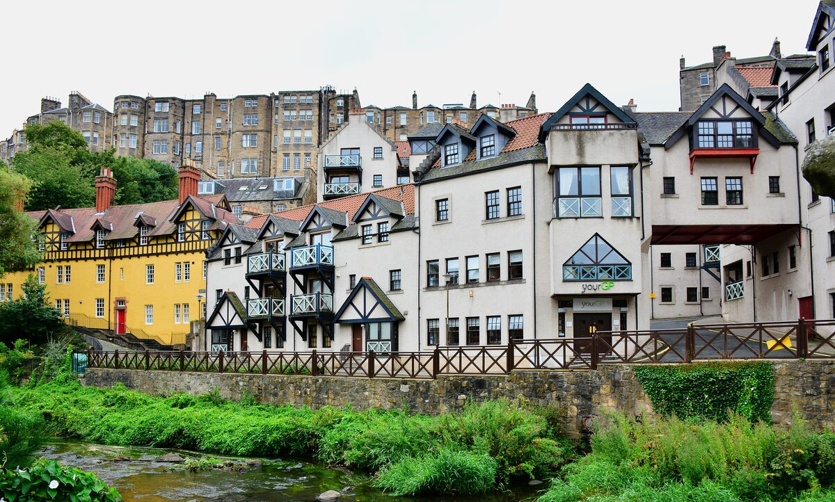Dean Village in Edinburgh, old houses with white and yellow walls above the green banks of the Water of Leith