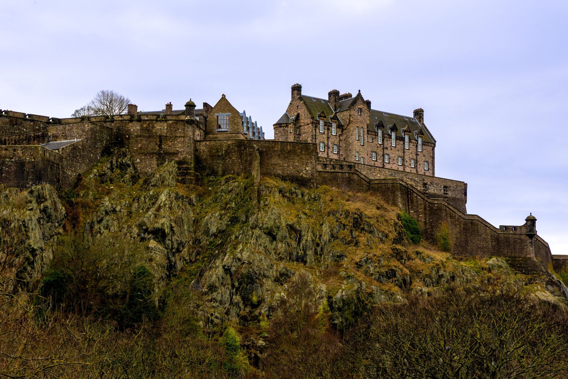 Edinburgh Castle on top of its dark volcanic rock, with buildings along the crag and a pale evening sky