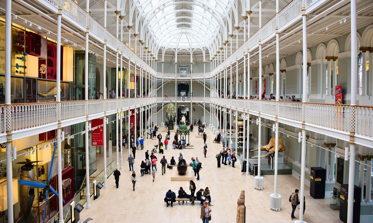 The bright Victorian Grand Gallery of the National Museum of Scotland, with white iron galleries under a glass roof