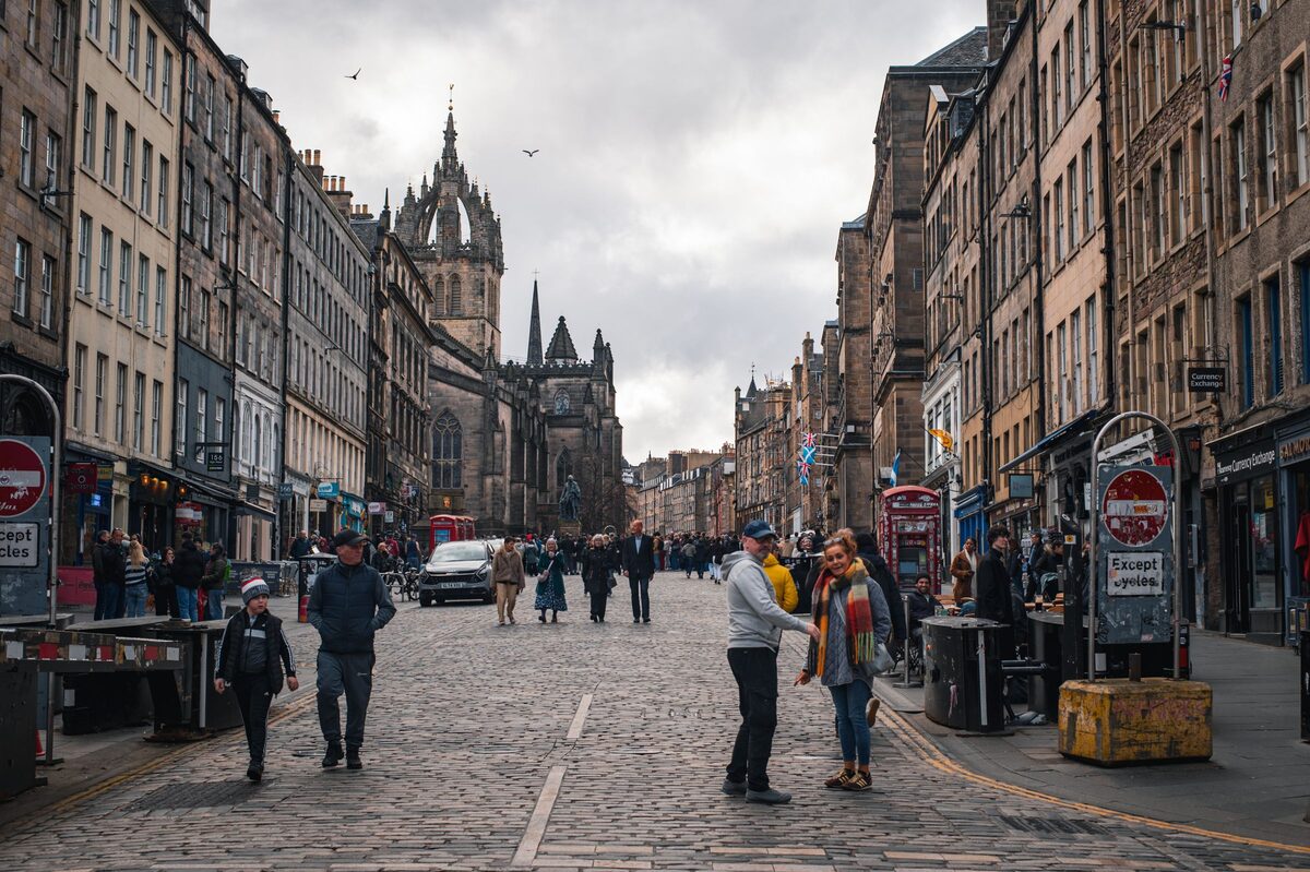 The cobbled Royal Mile in Edinburgh, lined with tall stone tenements, with the crown spire of St Giles' Cathedral ahead