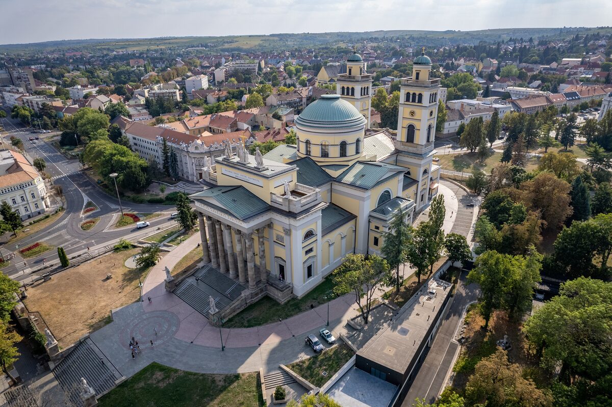Aerial view of Eger Basilica, with its columned portico, wide stairs, green dome and twin bell towers, and the town spreading behind it
