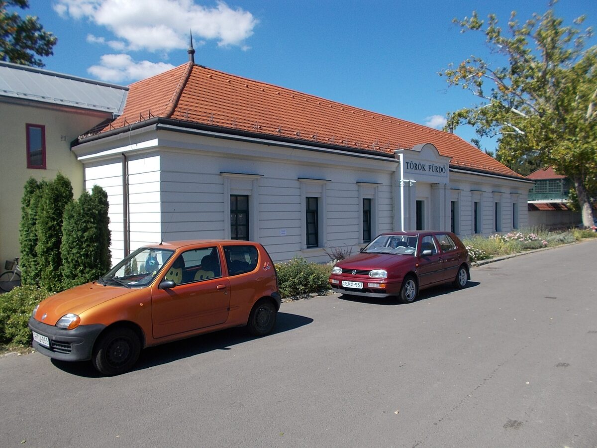 The white, red-roofed building of the Turkish Bath on Fürdő Street, with the Török fürdő sign over the entrance