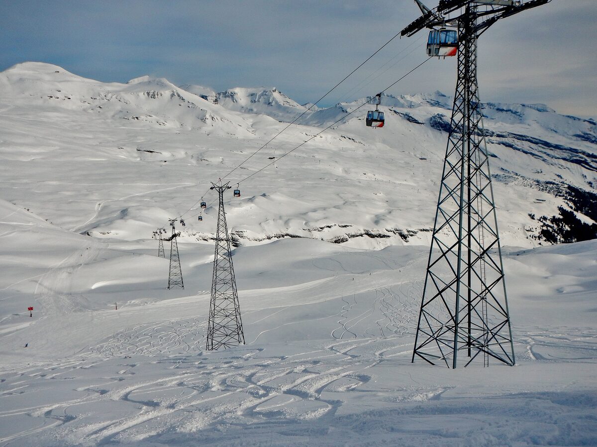 A gondola cabin above the snowy Vorab slopes, with the steel pylons of the lift running up the mountain