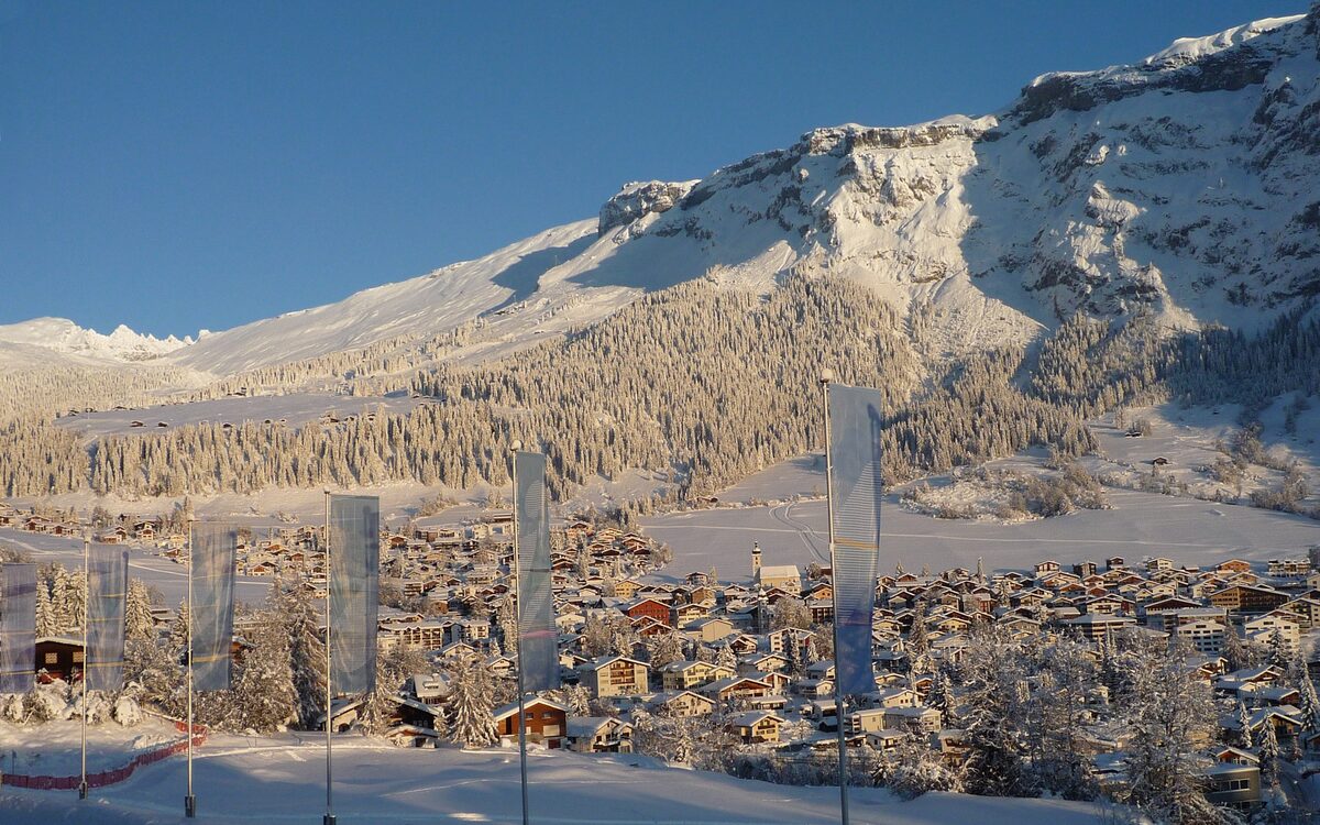 Flims in winter: village roofs under the snowy Flimserstein cliffs, seen from Waldhaus