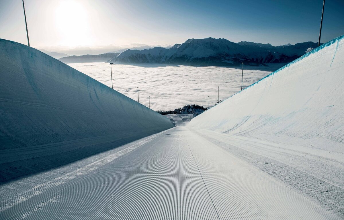 The groomed LAAX superpipe, with its tall snow walls and a sea of cloud beyond
