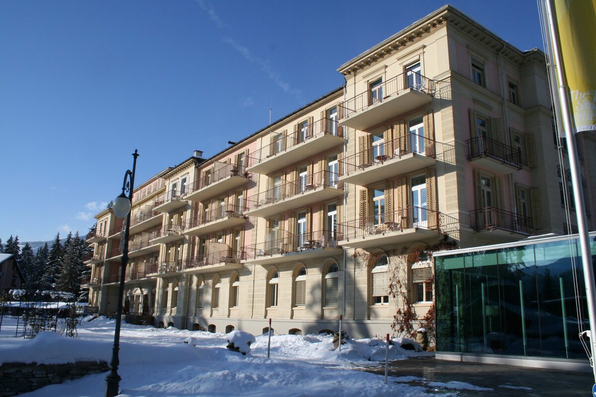 The Grand Hotel Waldhaus in Flims, a long pale facade with balconies, in deep snow under a blue sky