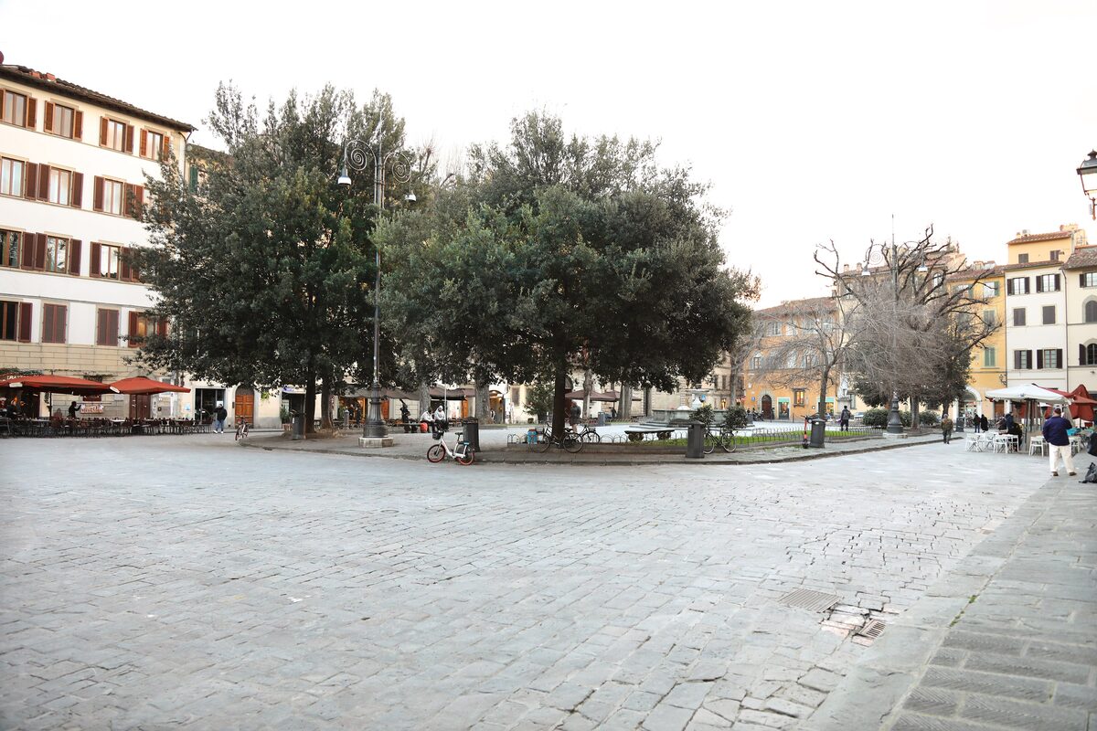 Piazza Santo Spirito in Florence, a wide paved square with trees, a fountain and café terraces in front of old houses
