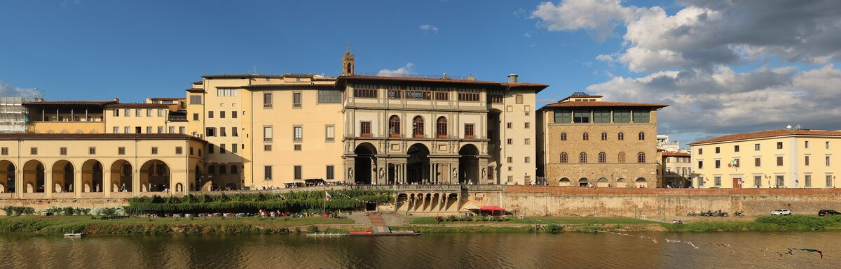 The long arcaded facade of the Uffizi seen across the river Arno, with the riverside walkway in front
