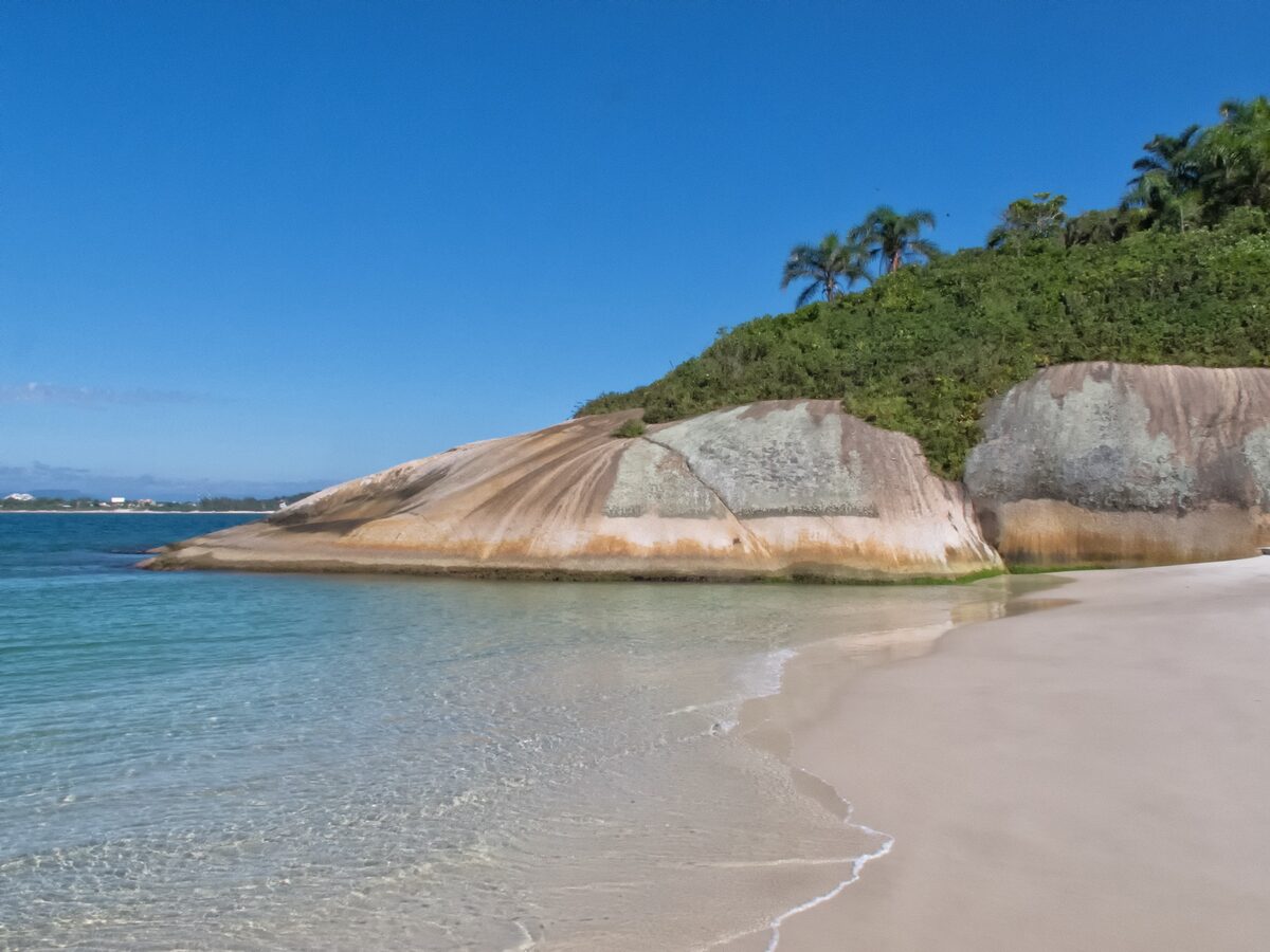 Beach on Campeche island: turquoise shallows, pink granite boulders and white sand under a blue sky