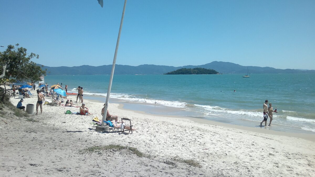 Canasvieiras beach on a sunny day: white sand, turquoise water and a small island on the horizon