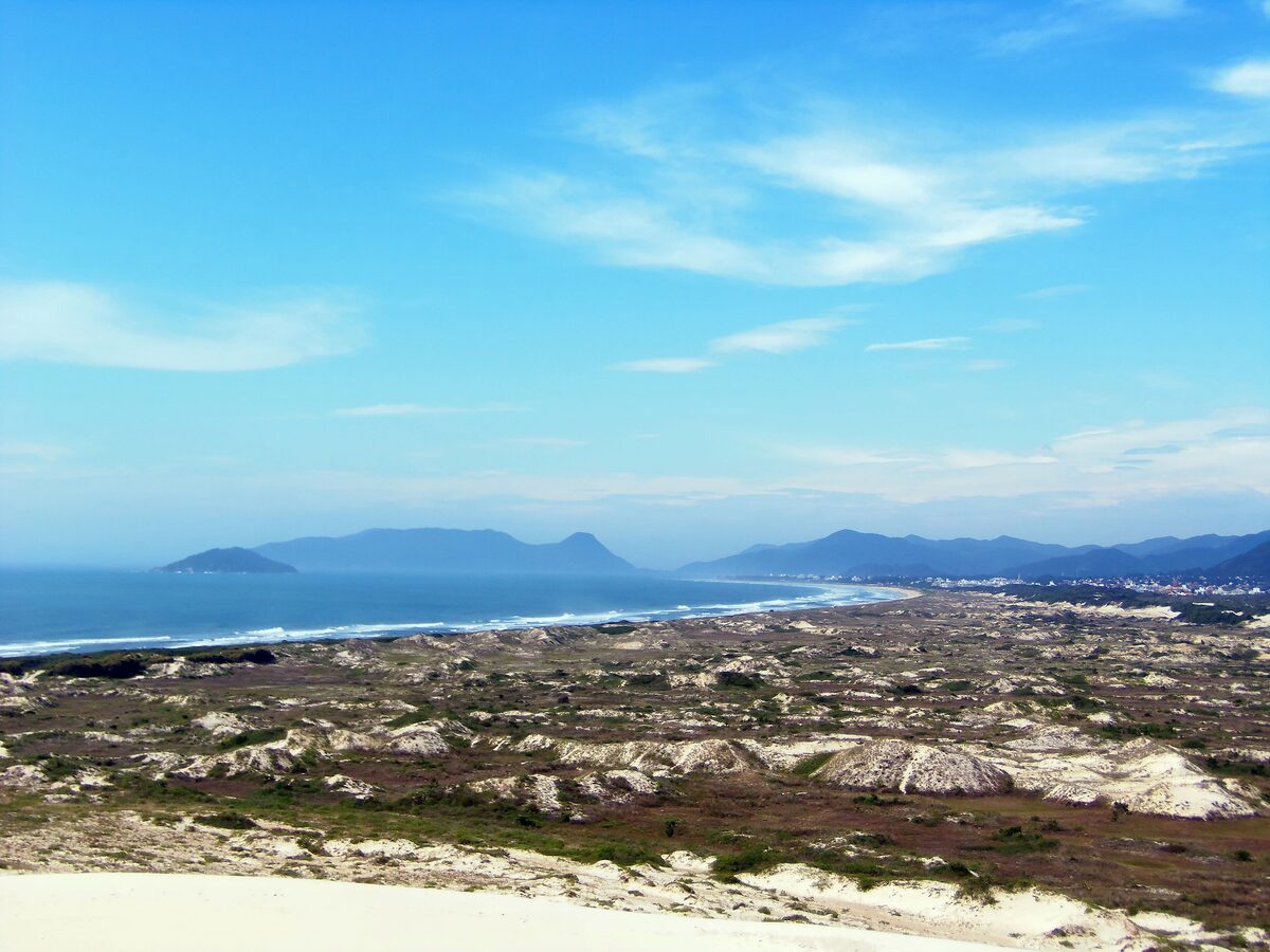 Sand dunes above Joaquina beach, with the Atlantic and hazy hills on the horizon