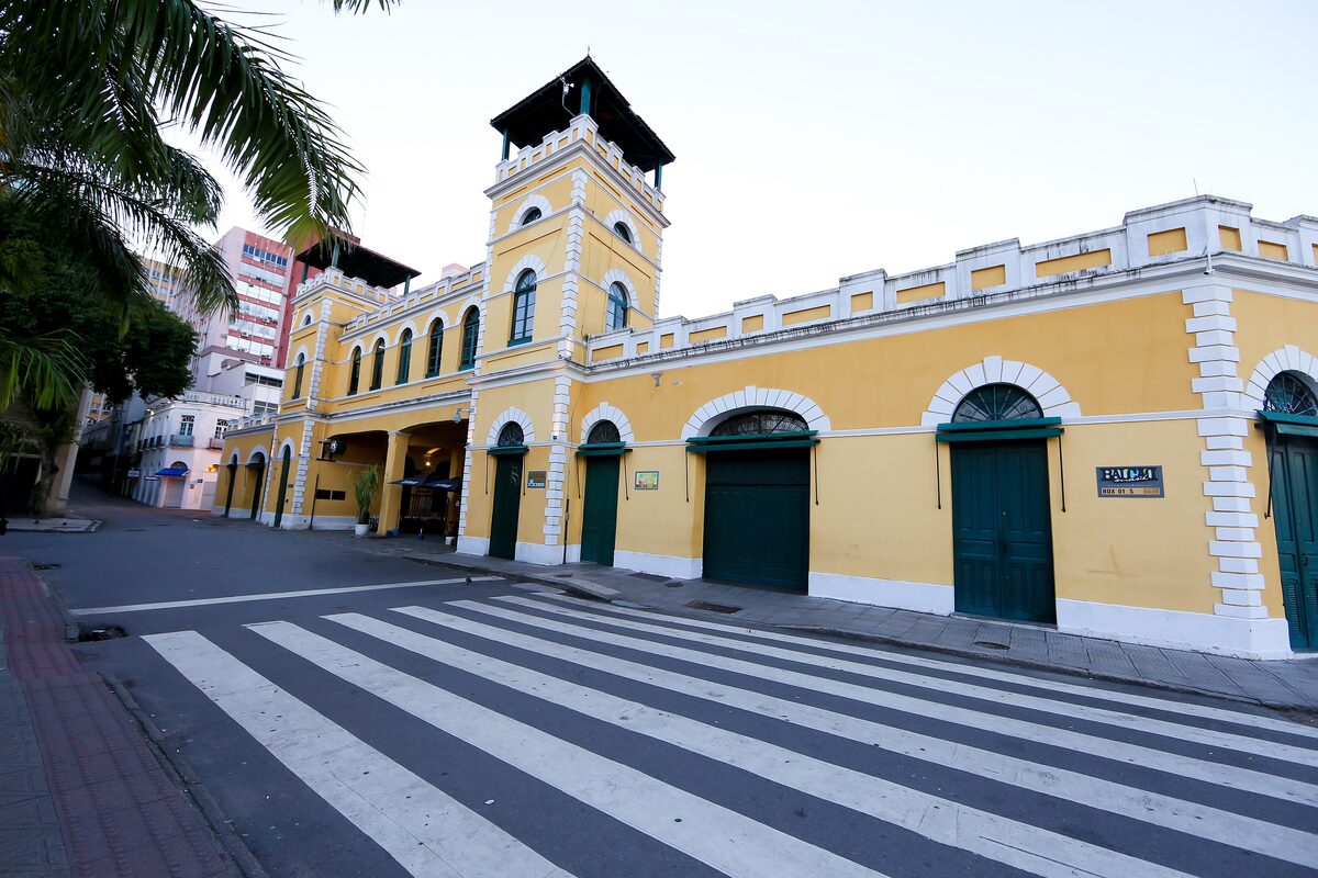 The yellow colonial facade of the Mercado Público with its clock tower, seen across a zebra crossing