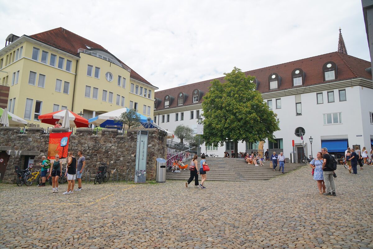 Cobbled Augustinerplatz with steps, market umbrellas and the old town houses around it