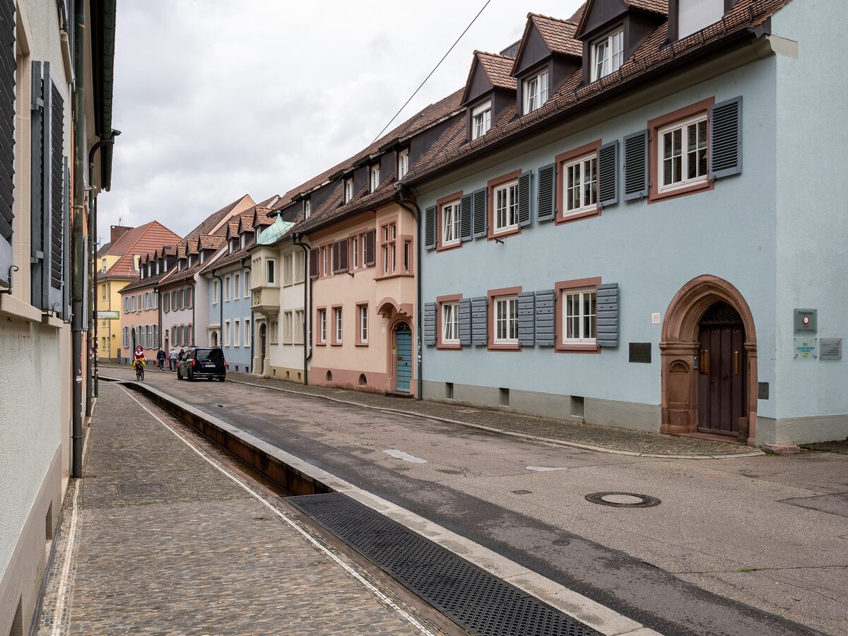 A narrow Bächle running along the pavement of Herrenstraße, with pastel old-town houses beside it