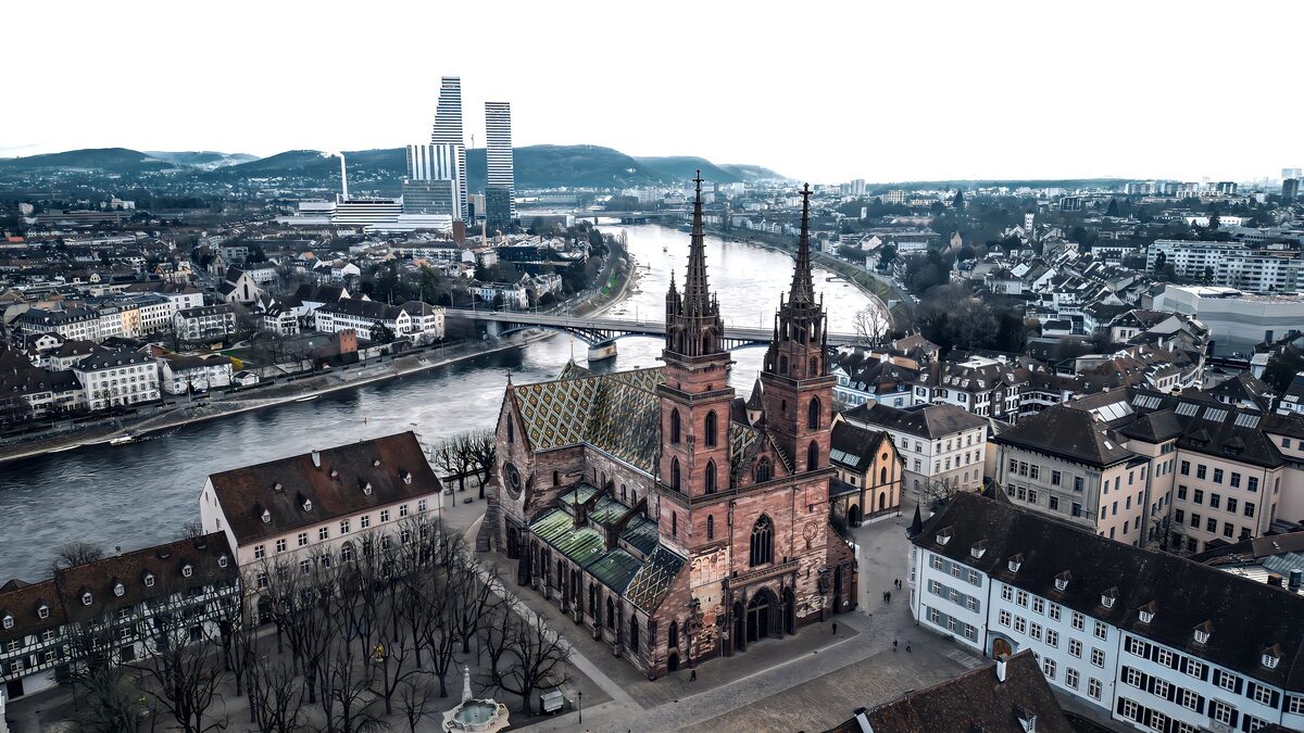Aerial view of Basel Minster with its two towers beside the Rhine, and the Roche towers on the skyline