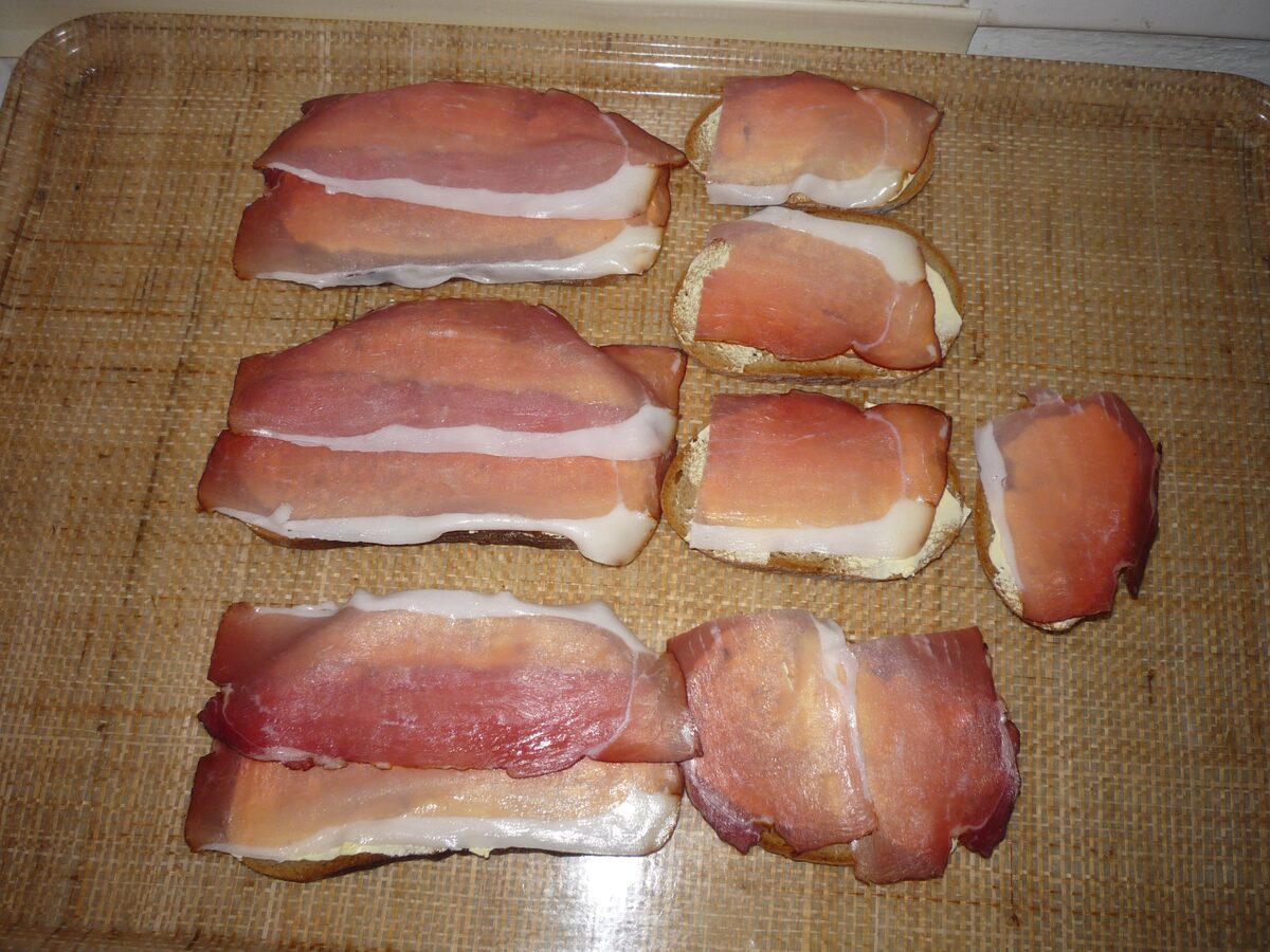 Thin slices of Black Forest ham laid on pieces of bread on a tray
