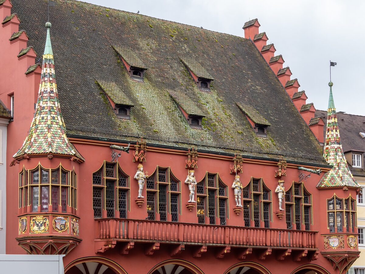 The red facade of the Historisches Kaufhaus with its oriel windows, tiled turrets and tiled roof