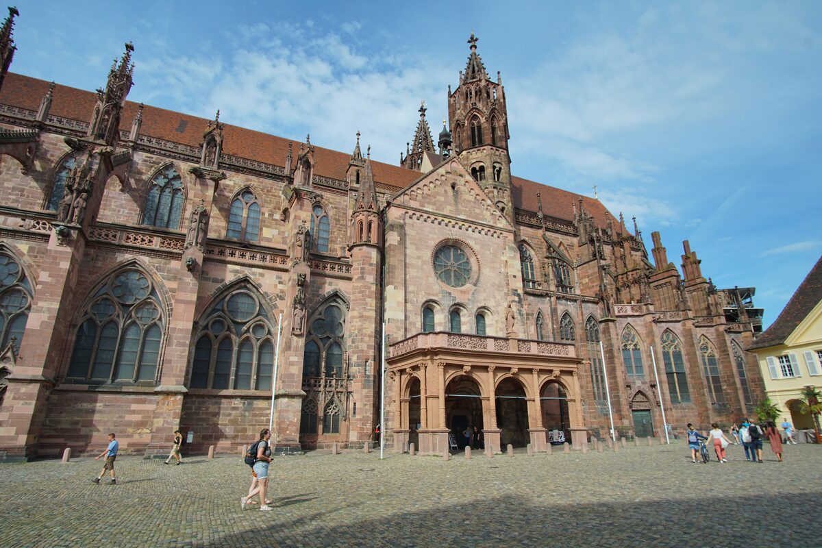 The south side of Freiburg Minster in red sandstone, seen from the cobbled Münsterplatz