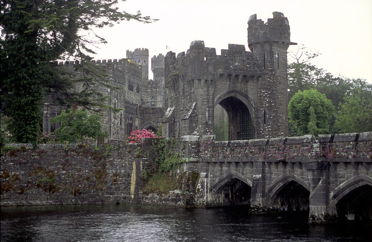 Ashford Castle in Cong, gray battlemented towers and a stone bridge with arches over the river