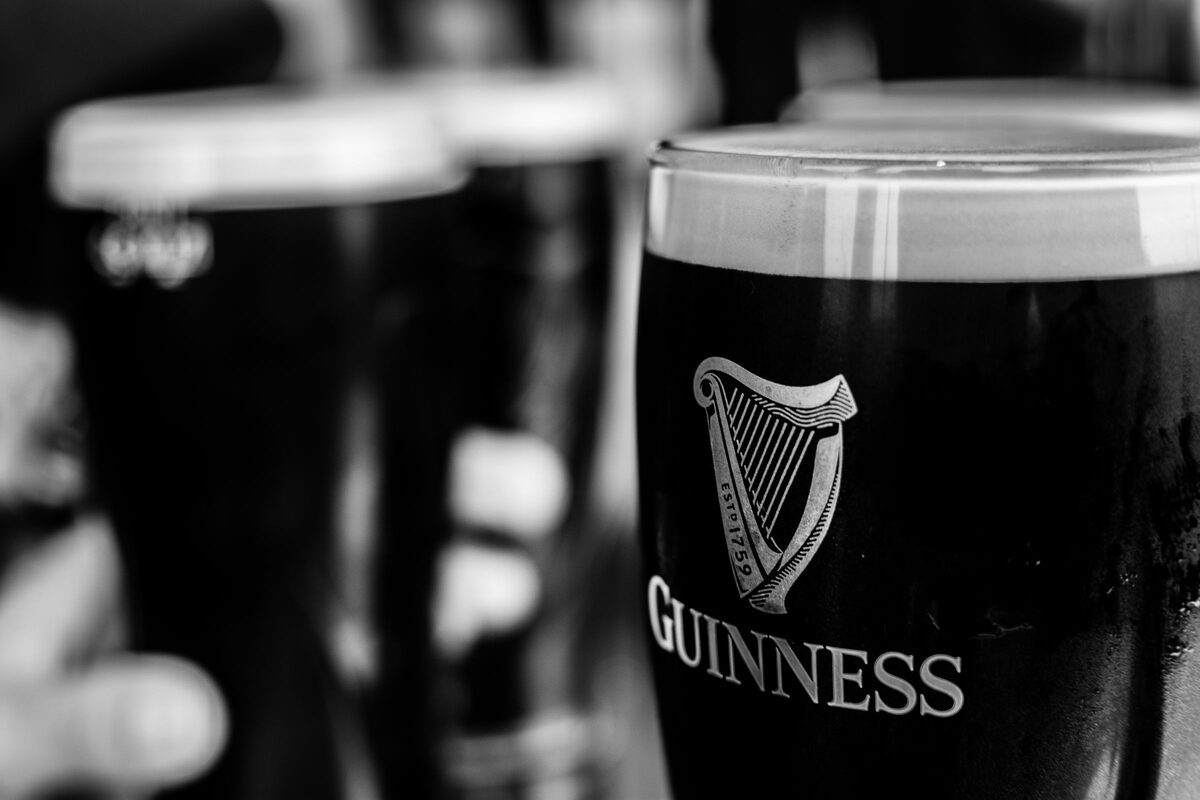 Black and white close-up of pints of Guinness with the harp logo on the glass