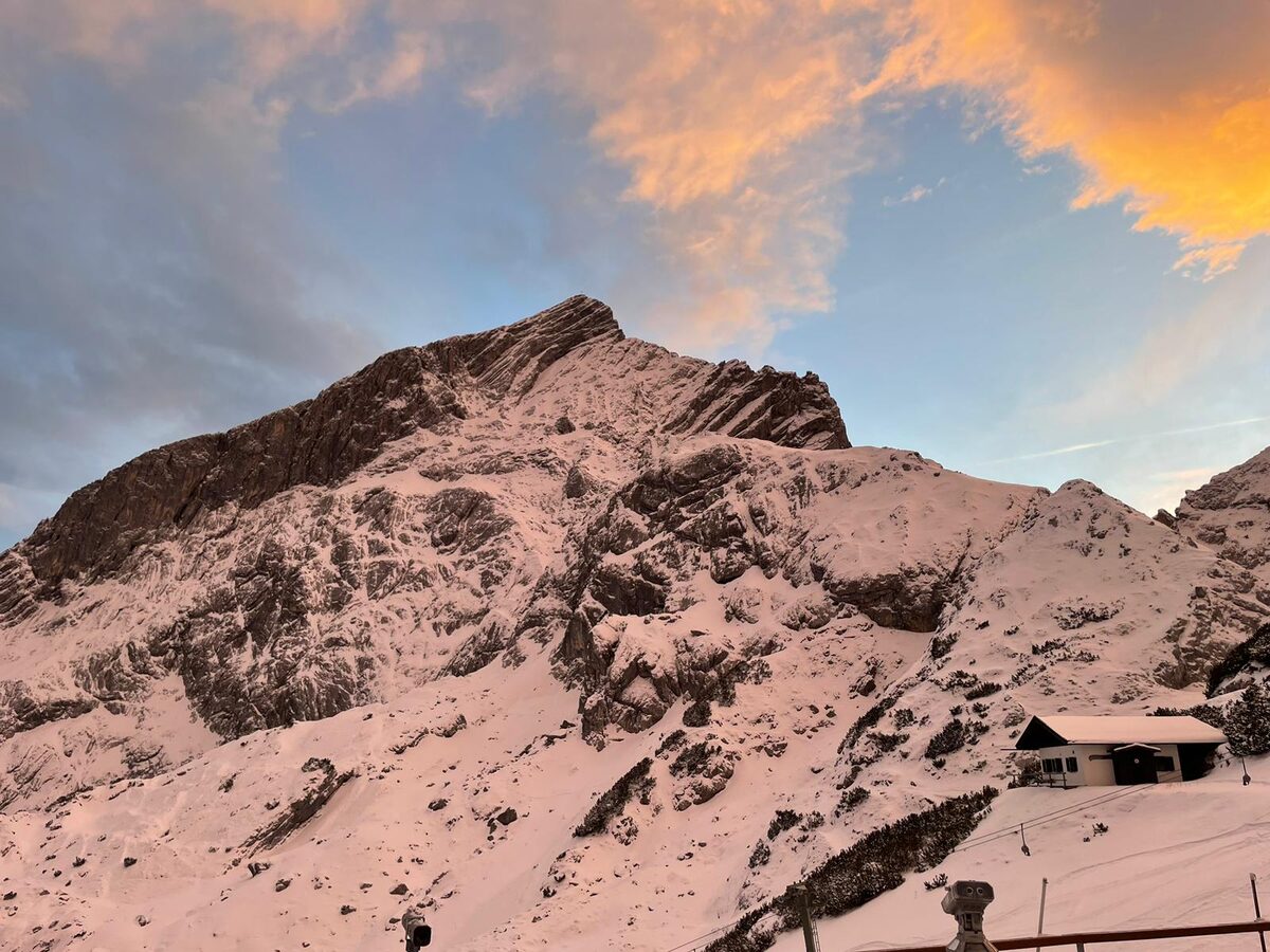 The Alpspitze in winter at sunset, with a snowy rock face and a hut below the summit