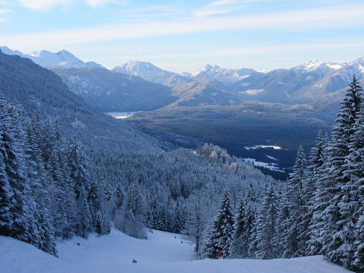 Snowy forest and mountains seen from the Kandahar run on a clear winter day, with a lake in the valley below