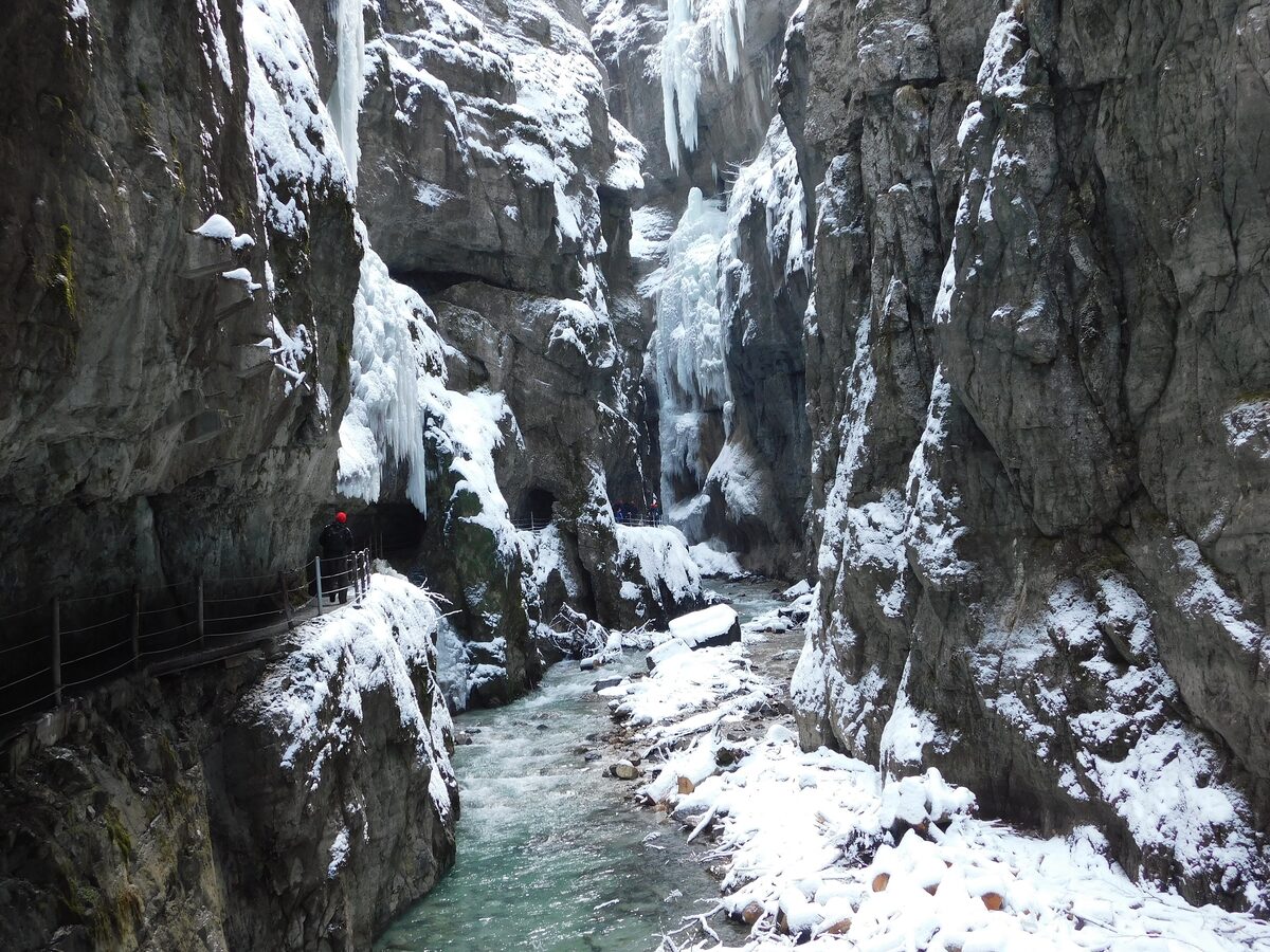 Icicles and snow inside the Partnachklamm gorge in winter, with the stream running below the walls