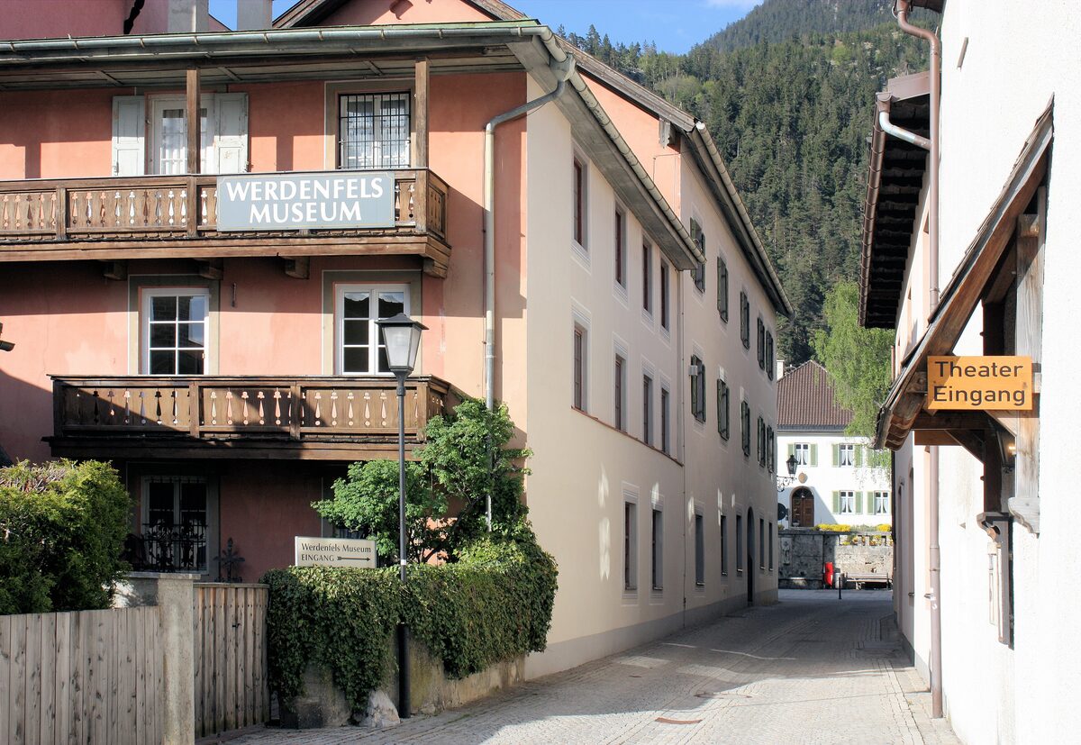 The Werdenfels Museum sign on a pink house with wooden balconies, on a quiet lane in Partenkirchen