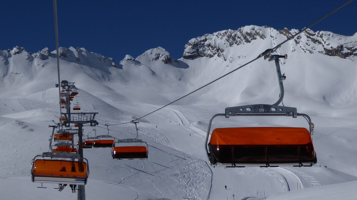 Orange chairlift chairs over the snowy Zugspitzplatt, with the jagged Wetterstein ridge on the horizon