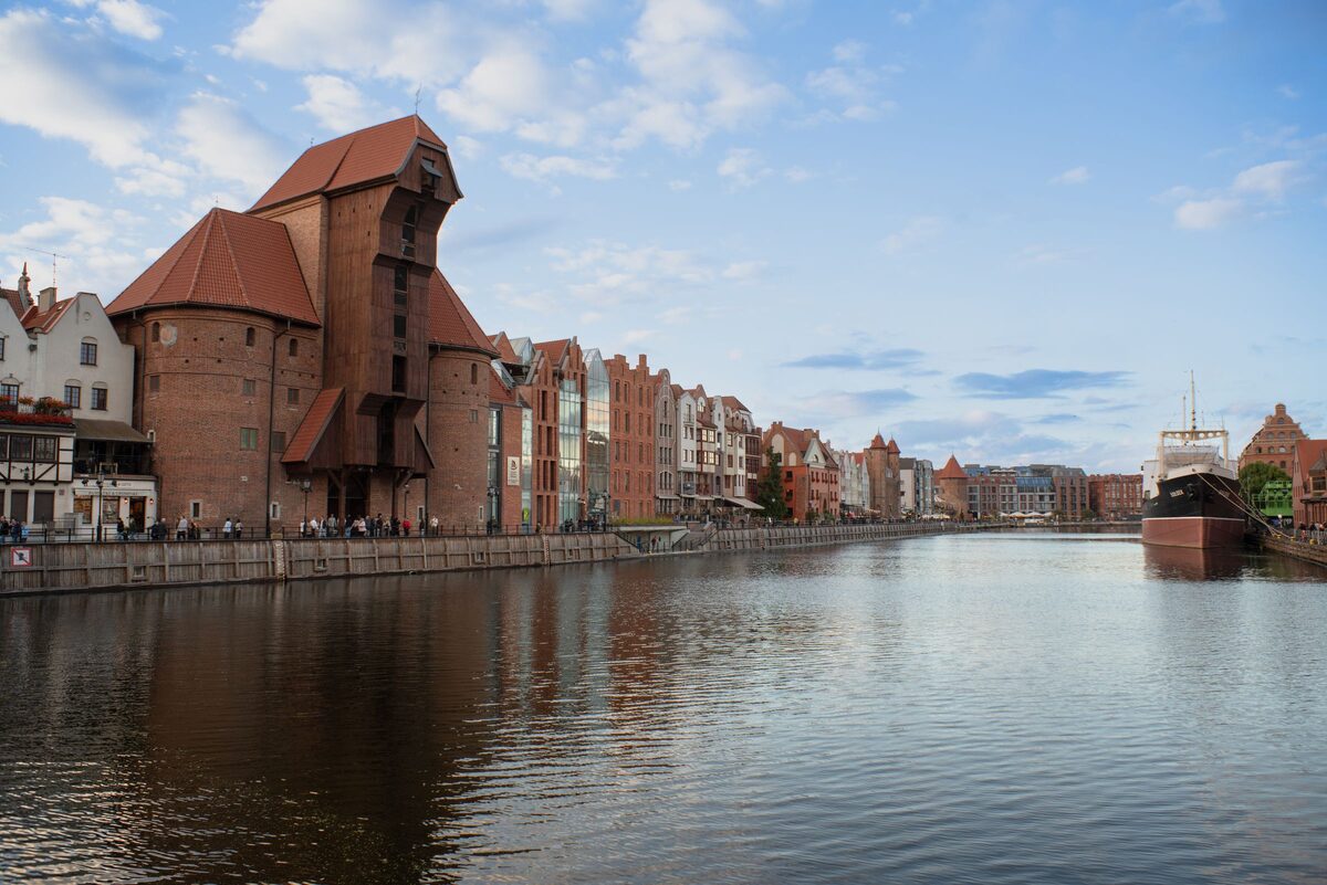 The brick Crane and the gabled houses of the Long Riverfront reflected in the Motława river