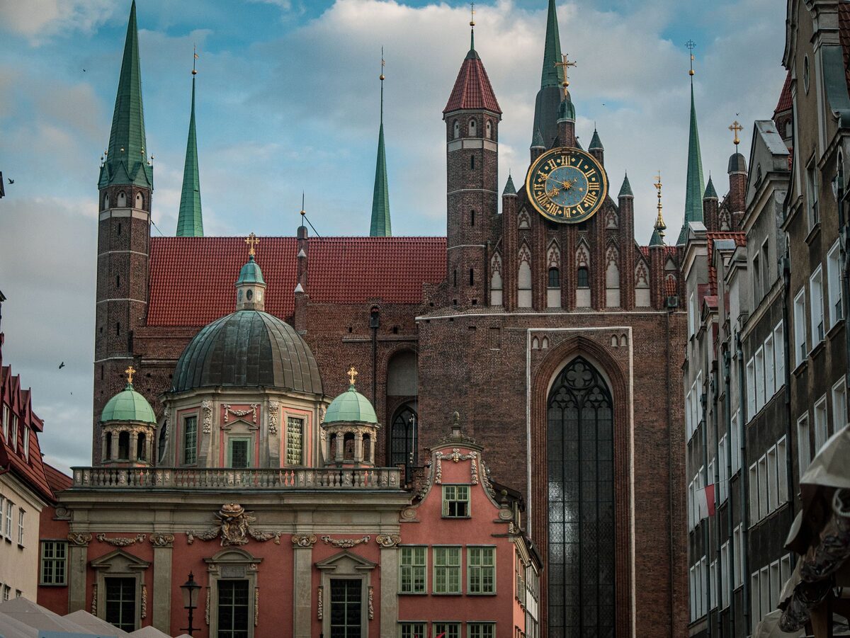 The brick facade of St. Mary's Basilica with its clock and slender spires, above the domed Royal Chapel