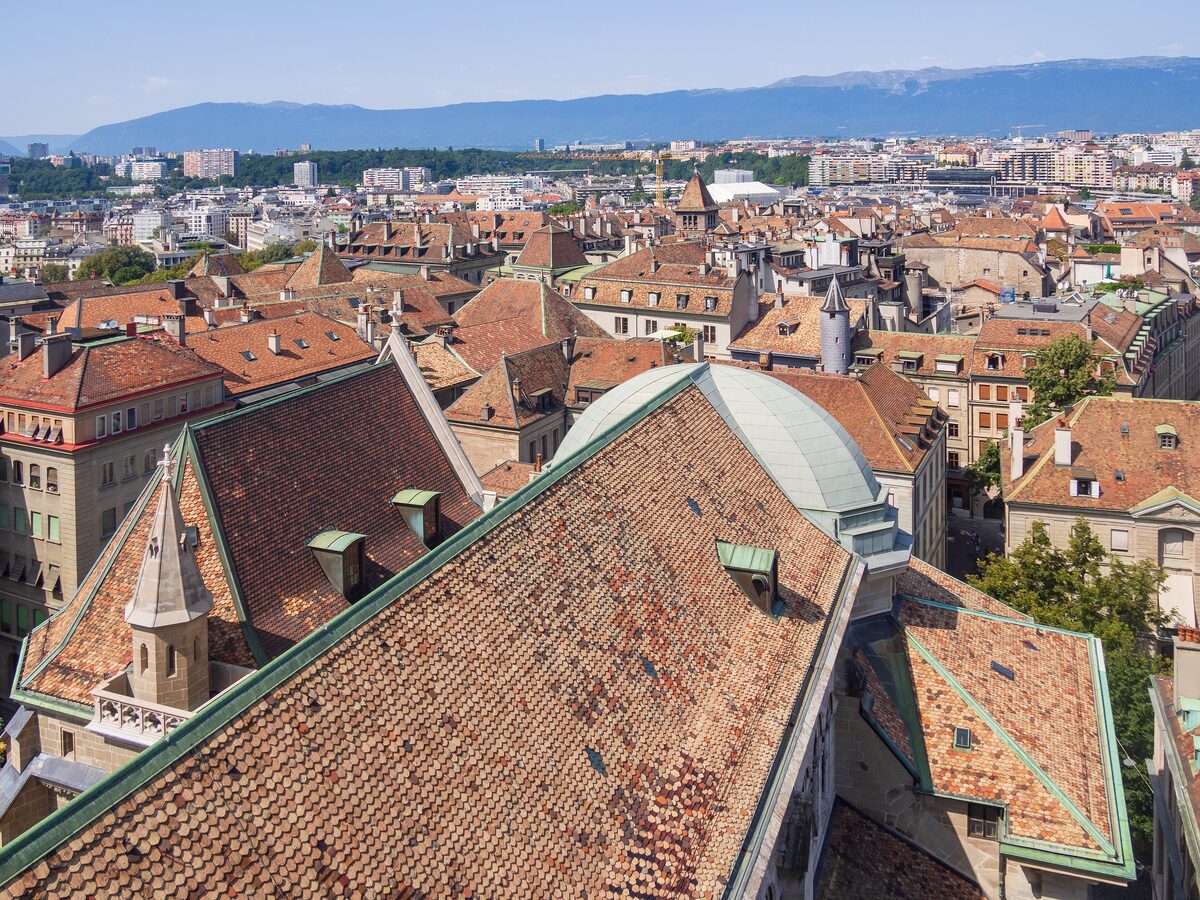 Red-tiled Old Town roofs and the cathedral roof seen from the top of St. Peter's, with the Jura on the horizon
