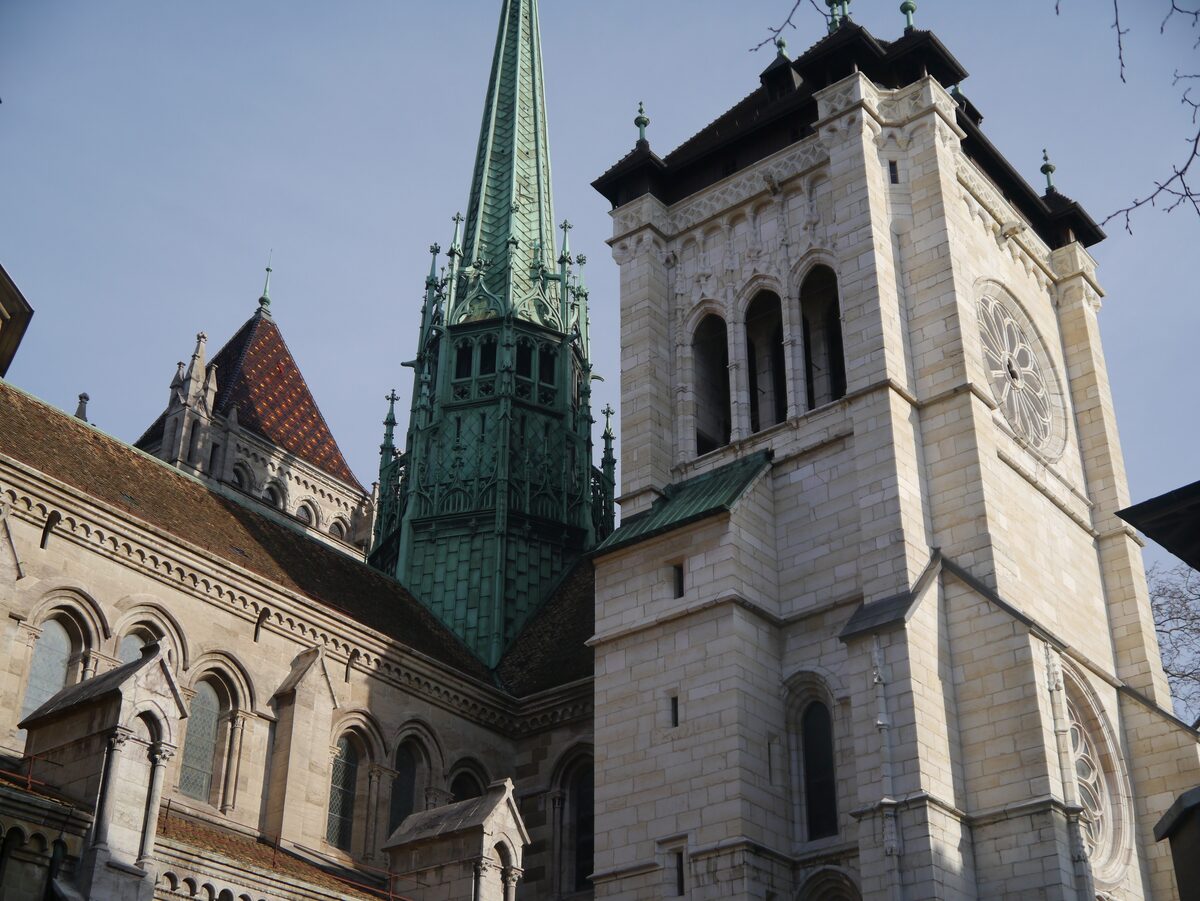 The white stone tower and green copper spire of St. Peter's Cathedral against a blue sky