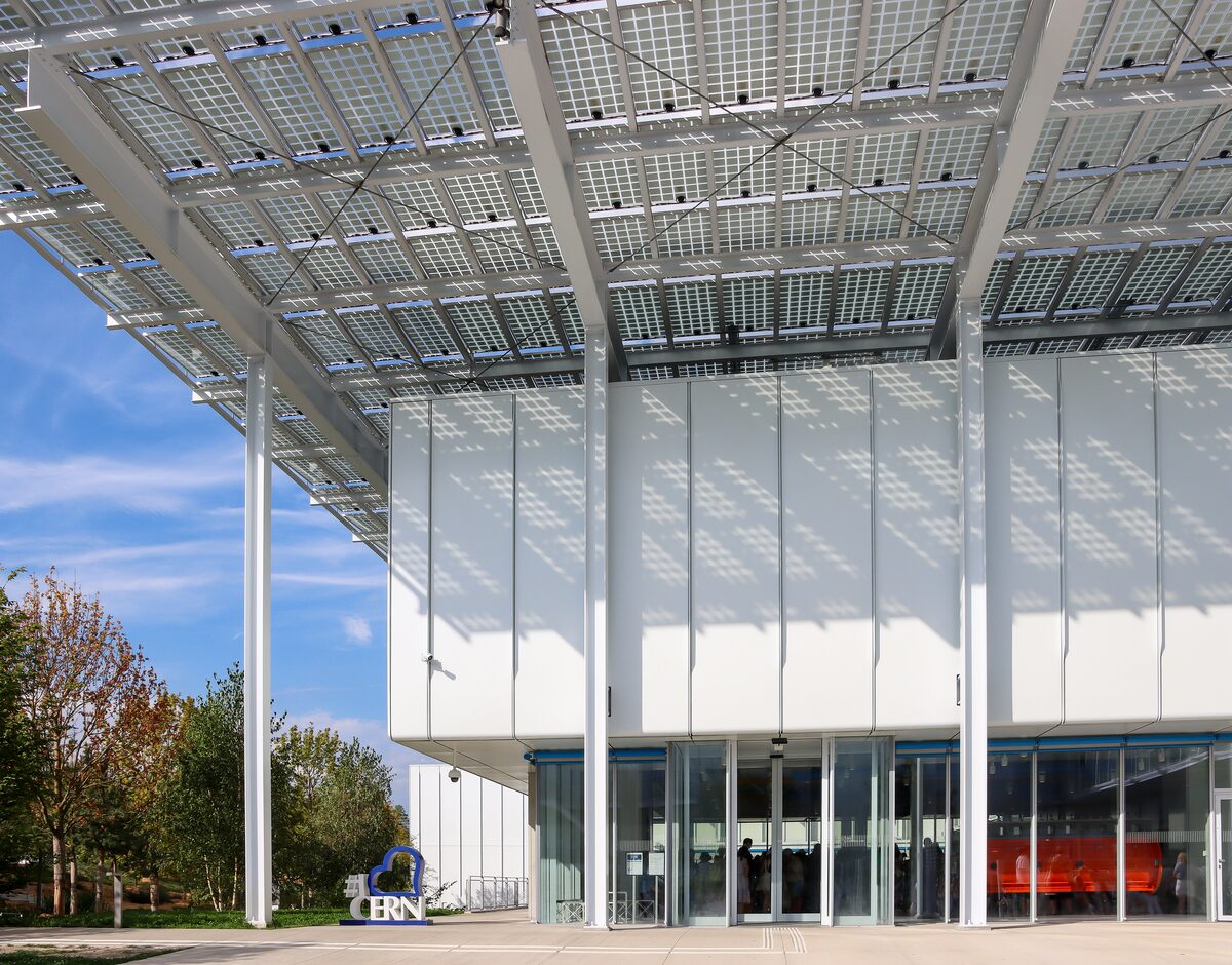 The glass entrance of the CERN Science Gateway under a canopy of solar panels