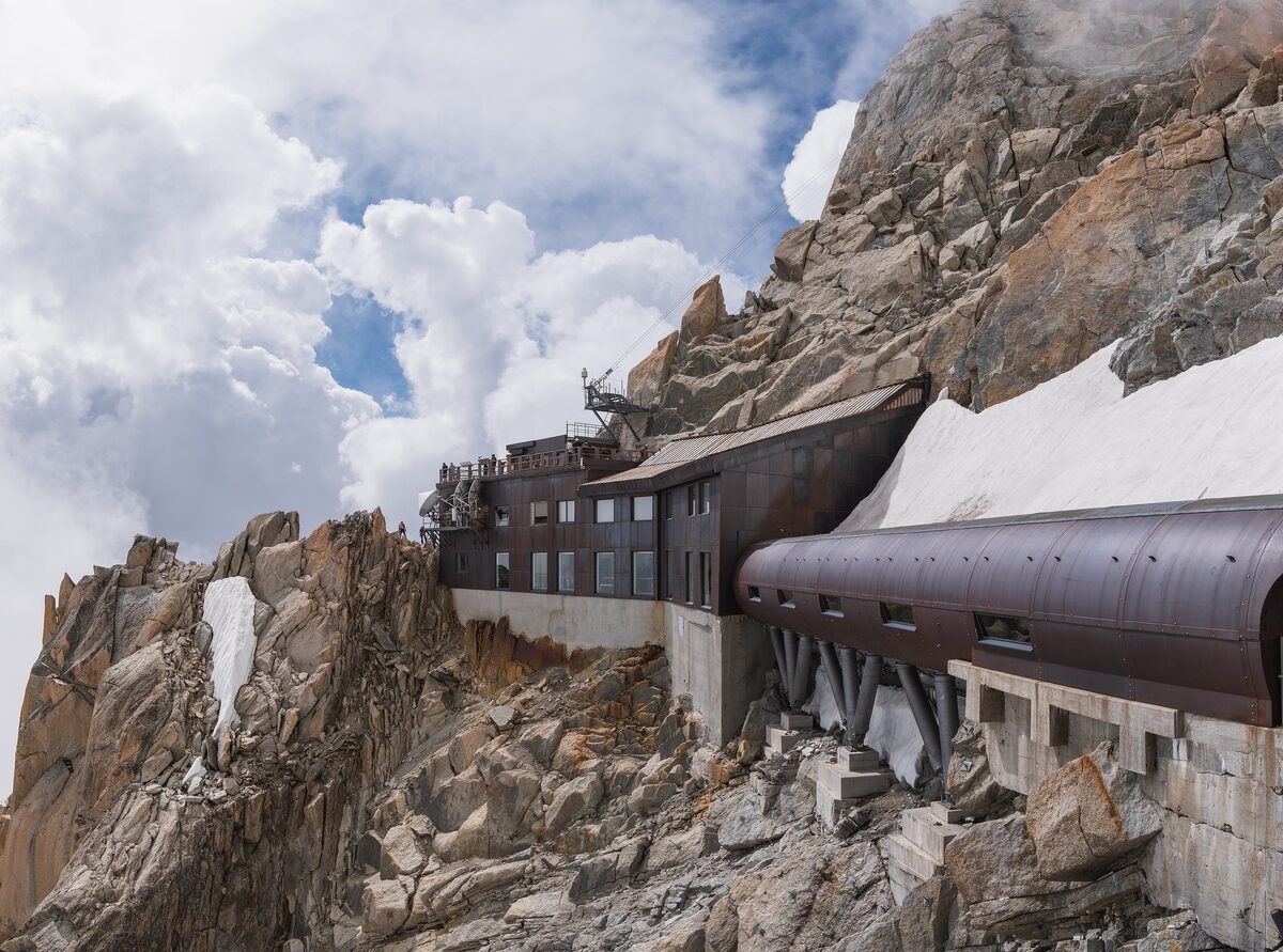 The Aiguille du Midi station and its covered walkway built into the granite rock, with snow and clouds above