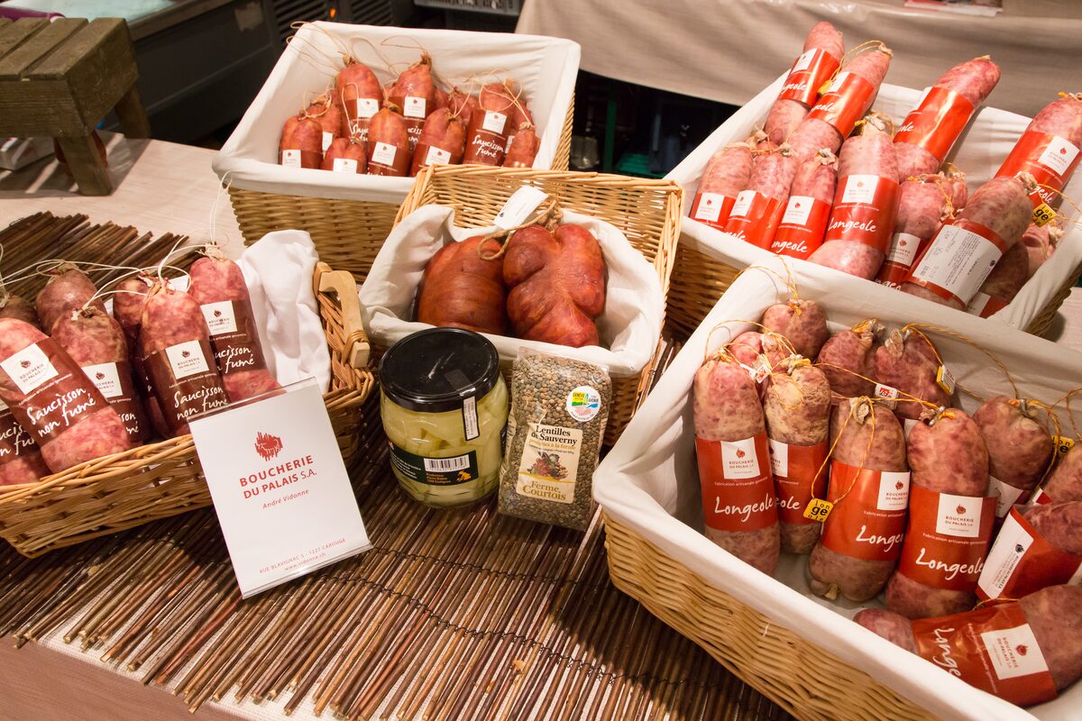 Baskets of Longeole sausages in red labeled packs on a Geneva producers' market stand