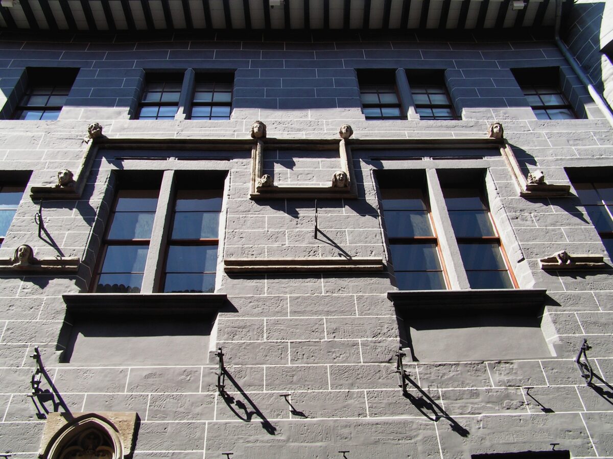 The grey stone facade of Maison Tavel with its tall windows and carved stone brackets