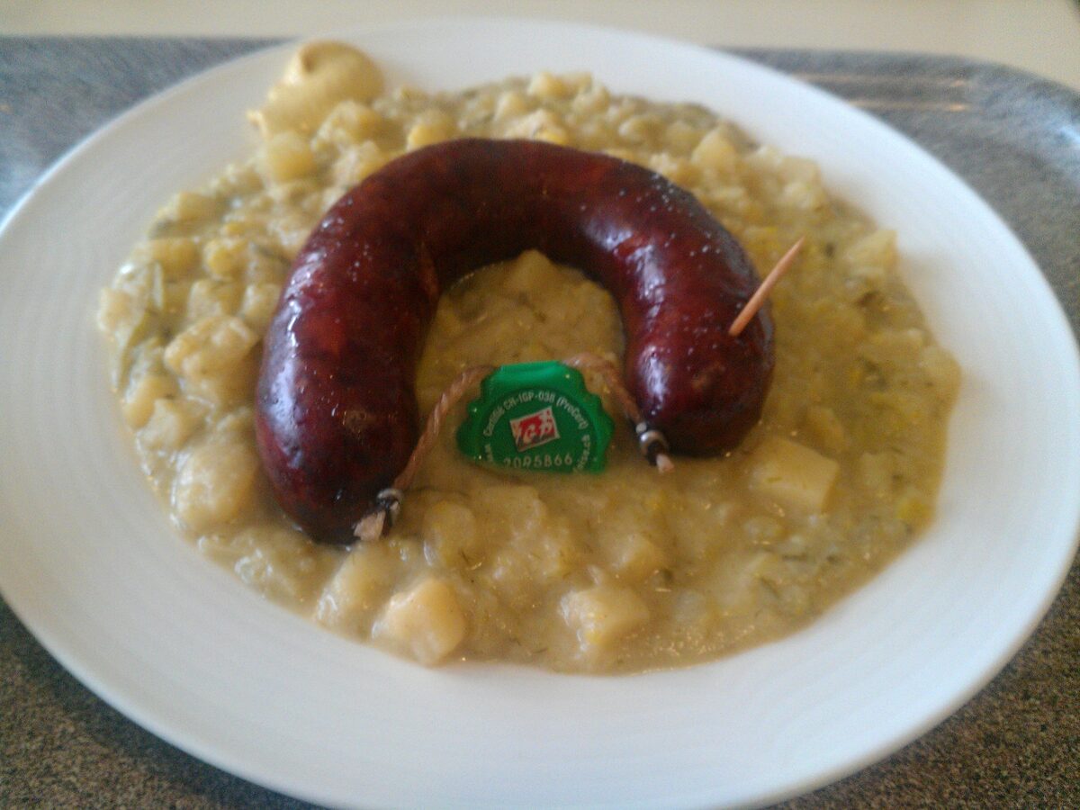 Leek and potato mash with a sausage on a white plate