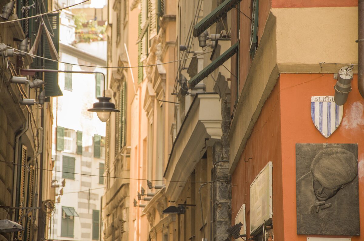A narrow caruggio between tall ochre and orange houses in the old town