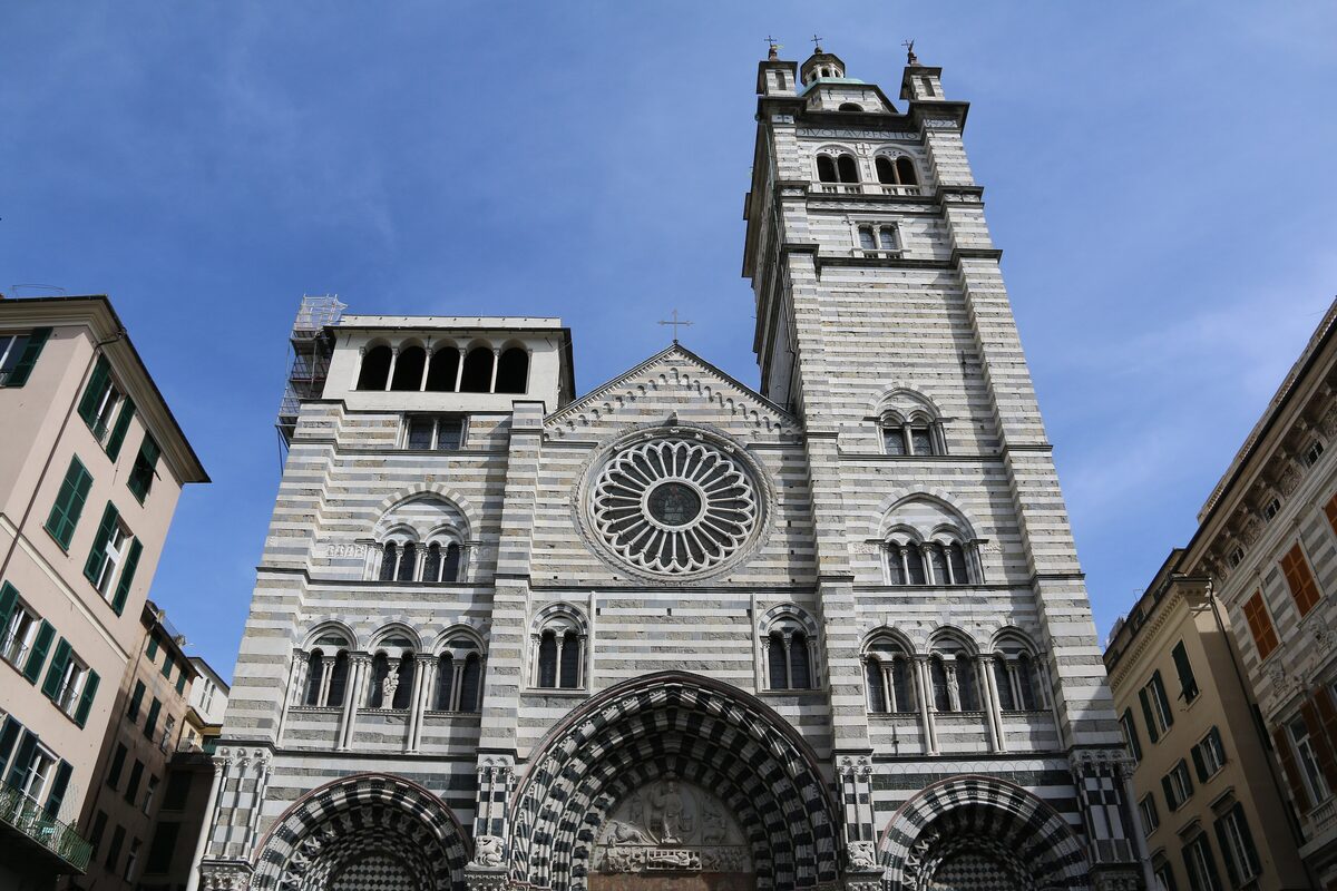 The black and white striped facade of Genoa Cathedral with its rose window and bell tower