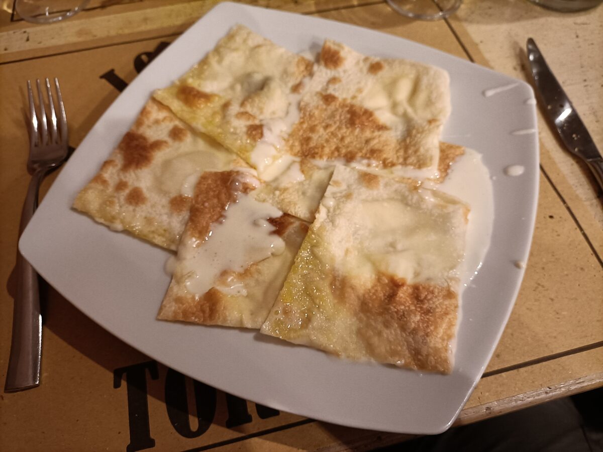 Thin focaccia di Recco with melted cheese cut into pieces on a plate